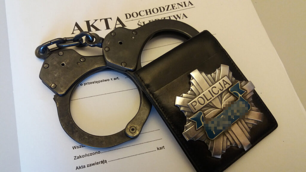 Kajdanki i odznaka policyjna na aktach dochodzenia