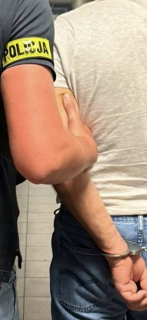 Policjant prowadzi zatrzymanego mężczyznę